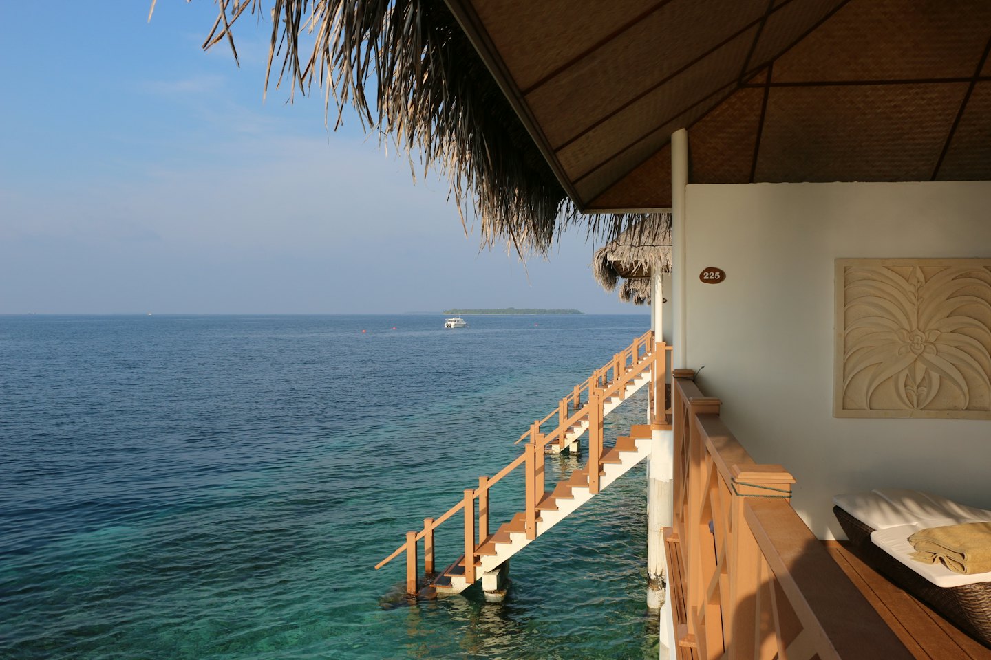 Escaleras de madera de un bungalow que dan directamente a aguas cristalinas de color turquesa.